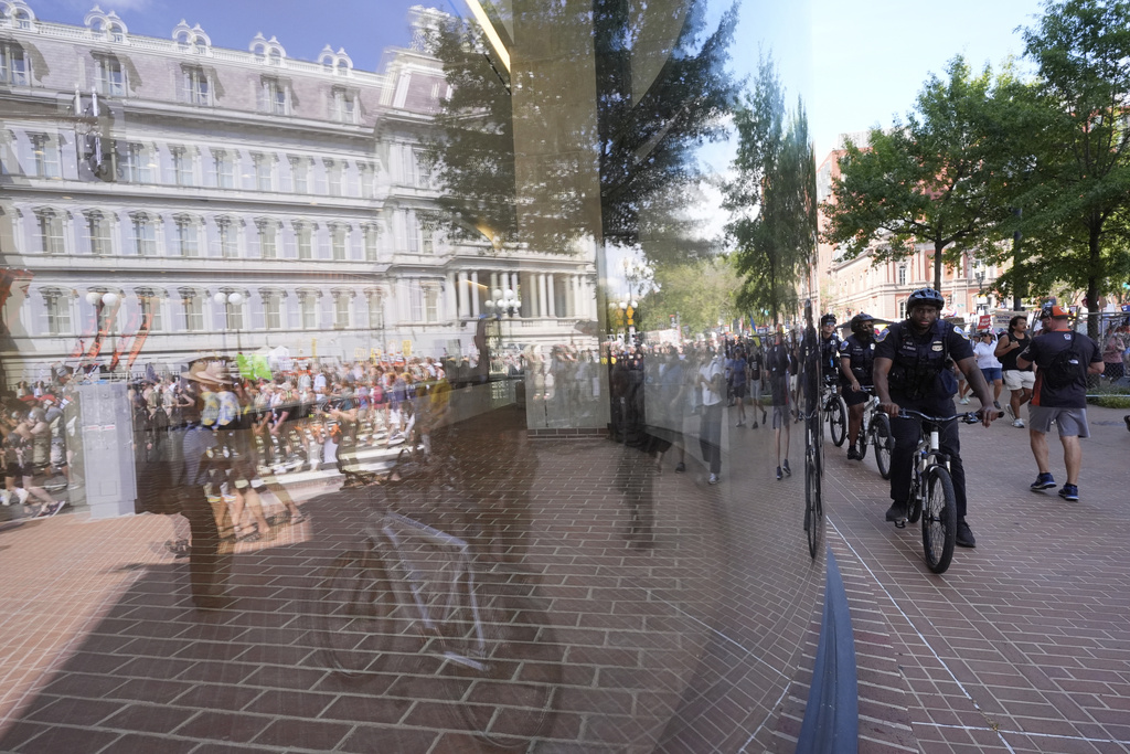 Police officers on bikes monitor events as activists march past the Executive Office Building on their way to the White House to protest President Donald Trump's federal takeover of policing of the District of Columbia, Saturday, Aug. 16, 2025, in Washington. (AP Photo/Alex Brandon)