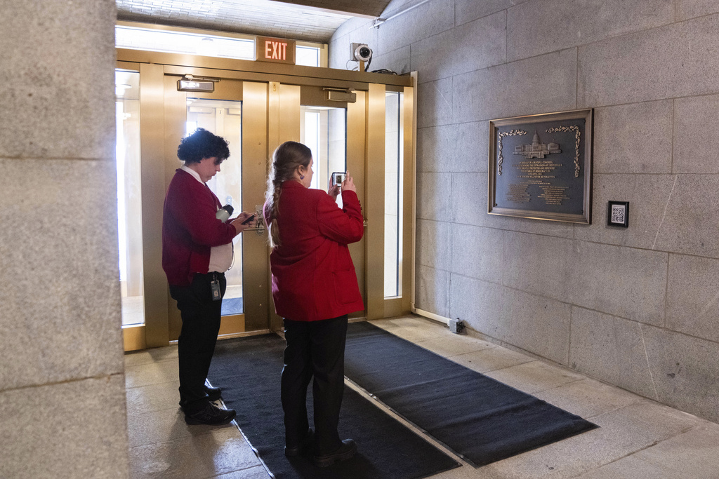 Capitol tour guides take photos of a plaque honoring police service on Jan. 6, 2021 at the Capitol, Saturday, March 7, 2026, in Washington. (AP Photo/Allison Robbert)