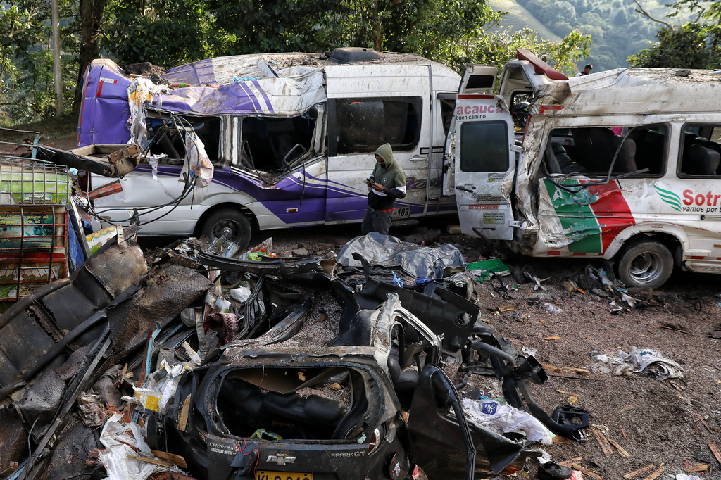 A man looks at vehicles damaged in an attack on the Pan-American Highway that killed at least a dozen people and authorities blamed on dissident groups of the former FARC rebels in Cajibio, Colombia, Sunday, April 26, 2026. (AP Photo/Santiago Saldarriaga)