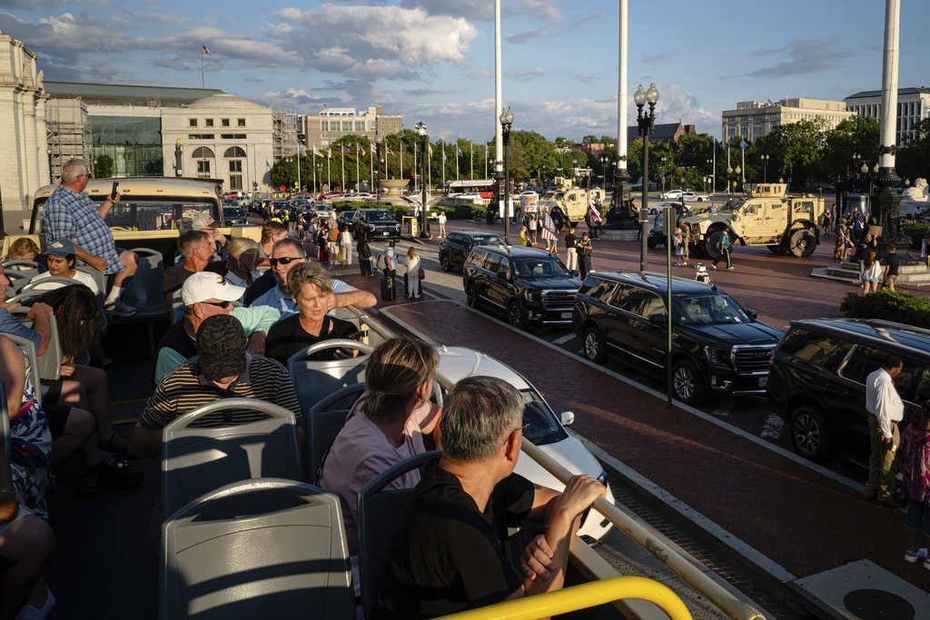 Riders on a tour bus look out over a protest and members of the DC National Guard at Union Station, Monday, Sept. 1, 2025, in Washington. (AP Photo/Jon Cherry)