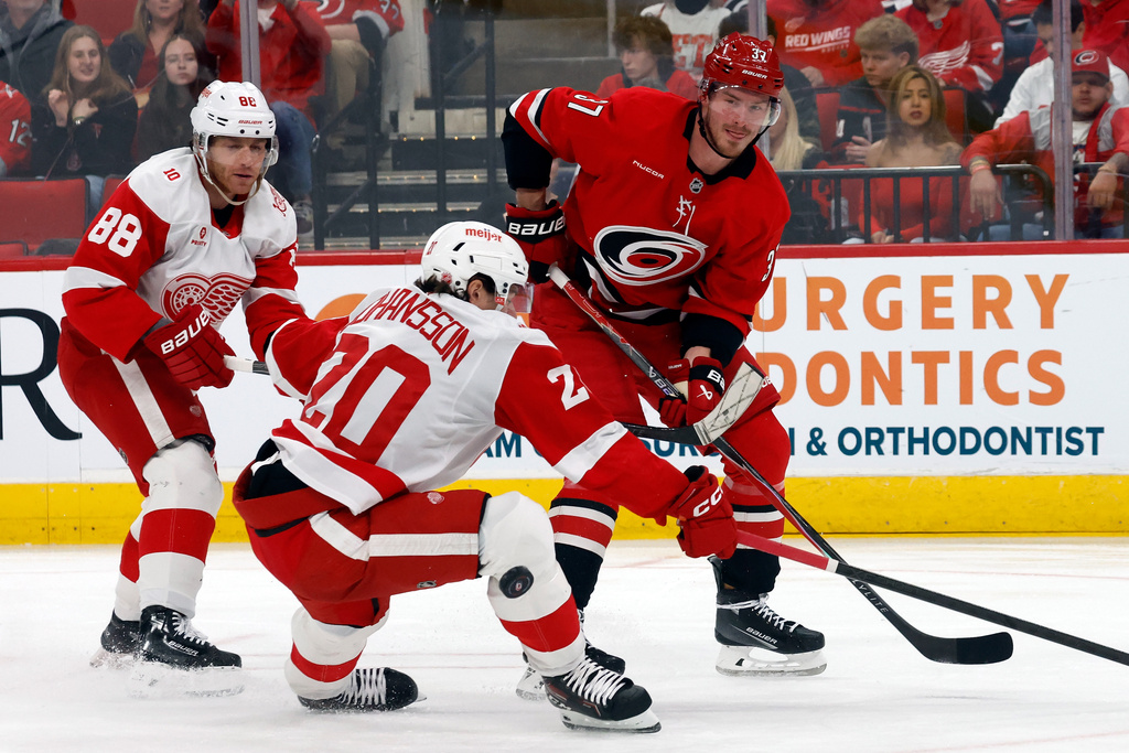 Carolina Hurricanes' Andrei Svechnikov (37) passes the puck around Detroit Red Wings' Albert Johansson (20) and Patrick Kane (88) during the second period of an NHL hockey game in Raleigh, N.C., Saturday, Feb. 28, 2026. (AP Photo/Karl DeBlaker)