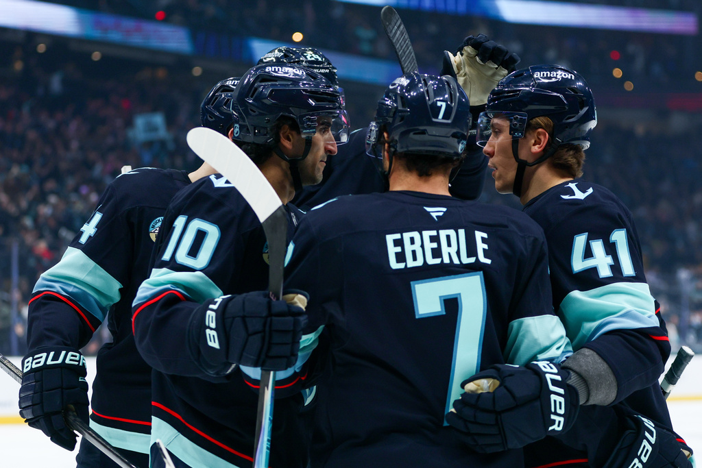 Seattle Kraken center Matty Beniers (10) is embraced by teammates after scoring in the first period against the Nashville Predators during an NHL hockey game Thursday, Jan. 1, 2026, in Seattle. (AP Photo/Kevin Ng)