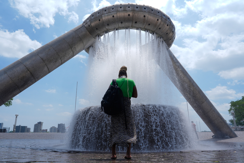 A woman stands in mist trying to cool off from hot weather at Dodge Fountain at Hart Plaza in Detroit, Tuesday, June 30, 2026. (AP Photo/Paul Sancya)