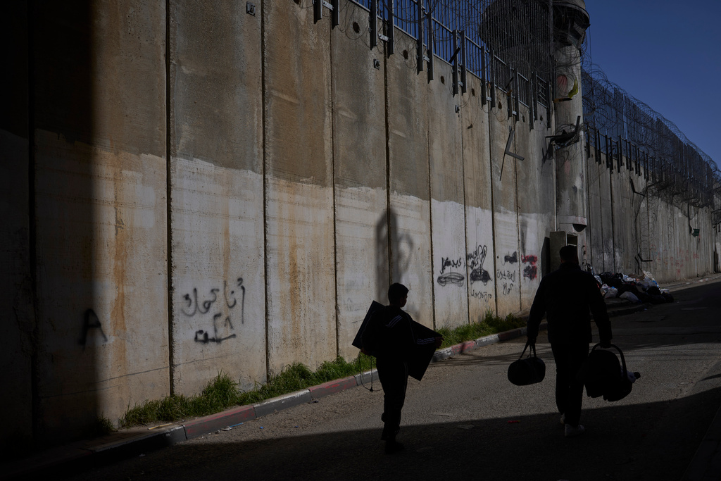 Palestinians walk along the separation barrier between the West Bank and east Jerusalem neighborhood of Beit Hanina, Sunday Feb. 15, 2026. (AP Photo/Ohad Zwigenberg)