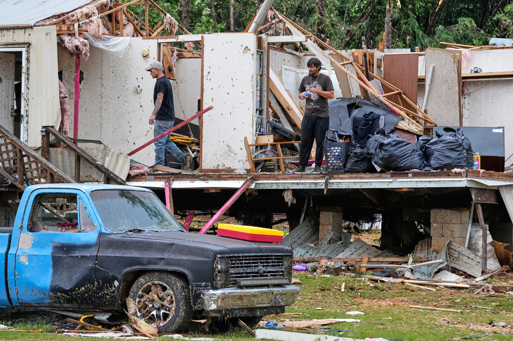 People stand among debris at Gene's Mobile Home Supply, a trailer park in Bogue Chitto, Miss., Thursday, May, 7, 2026, after a tornado cut across the state. (AP Photo/Gerald Herbert)