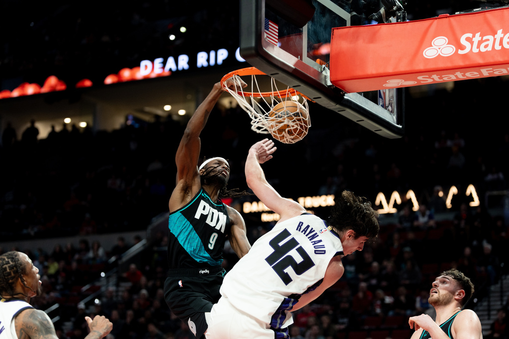 Portland Trail Blazers forward Jerami Grant, left, dunks the ball against Sacramento Kings center Maxime Raynaud, right, during the second half of an NBA basketball game Thursday Dec. 18, 2025, in Portland, Ore. (AP Photo/Howard Lao)