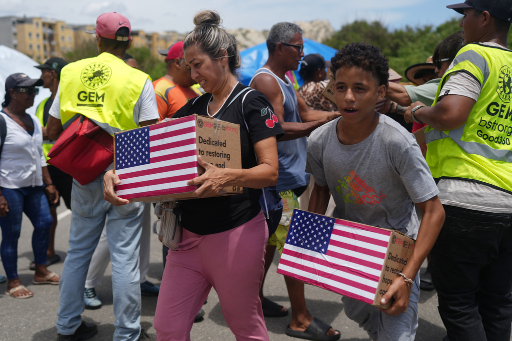 People affected by the earthquakes carry U.S. humanitarian aid after receiving it in La Guaira, Venezuela, Wednesday, July 8, 2026. (AP Photo/Ariana Cubillos)