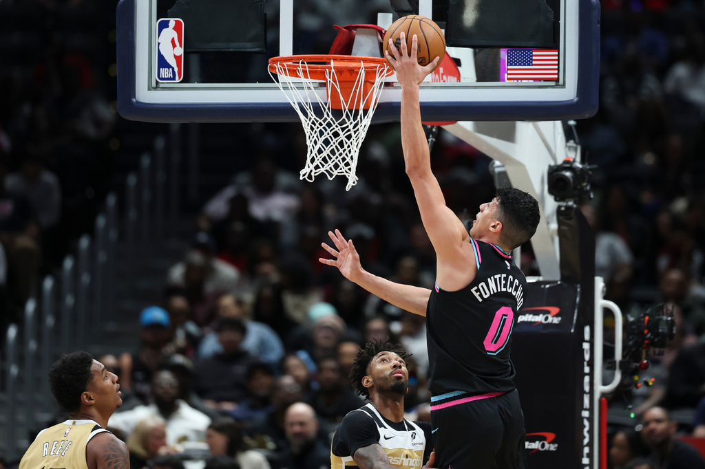 Miami Heat forward Simone Fontecchio (0) goes to the basket for a layup over Washington Wizards forward Leaky Black, second from right, during the first half of an NBA basketball game, Friday, April 10, 2026, in Washington. (AP Photo/Terrance Williams)
