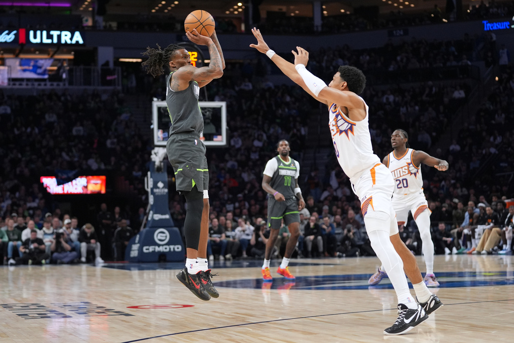 Minnesota Timberwolves guard Bones Hyland, left, shoots over Phoenix Suns forward Ryan Dunn during the first half of an NBA basketball game, Tuesday, March 17, 2026, in Minneapolis. (AP Photo/Abbie Parr)