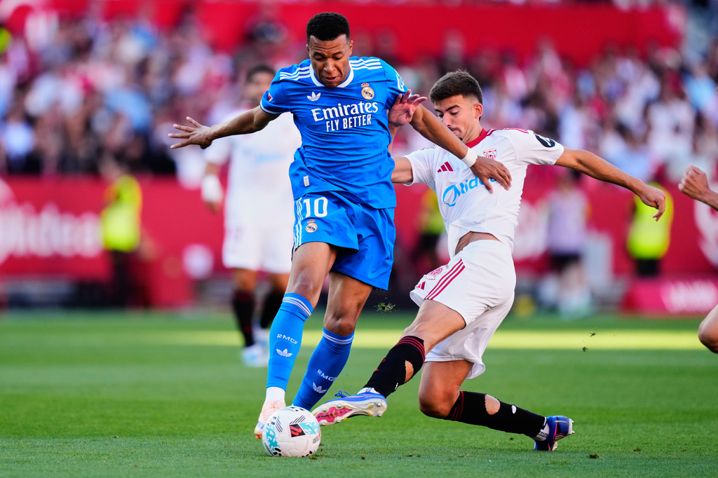 Real Madrid's Kylian Mbappe, left, duels for the ball with Sevilla's Kike Salas during the Spanish La Liga soccer match at the Ramon Sanchez Pizjuan stadium in Seville, Spain, Sunday, May 17, 2026. (AP Photo/Jose Breton)