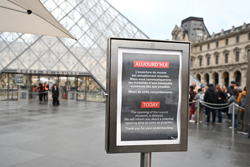 A board reads that the opening of the Louvre museum is delayed, but it remains closed for the day after Sunday's jewels robbery, Monday, Oct. 20, 2025 in Paris. (AP Photo/Emma Da Silva)