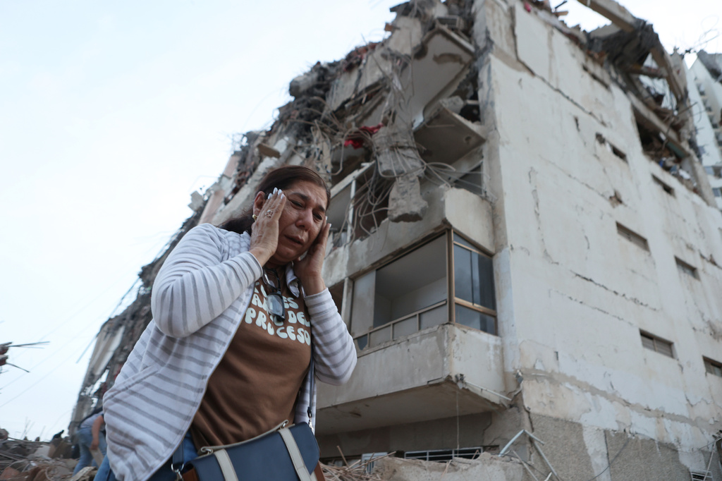 FILE - A woman walks past a quake-damaged building in La Guaira, Venezuela, June 25, 2026, a day after twin earthquakes struck the country. (AP Photo/Pedro Mattey, File)