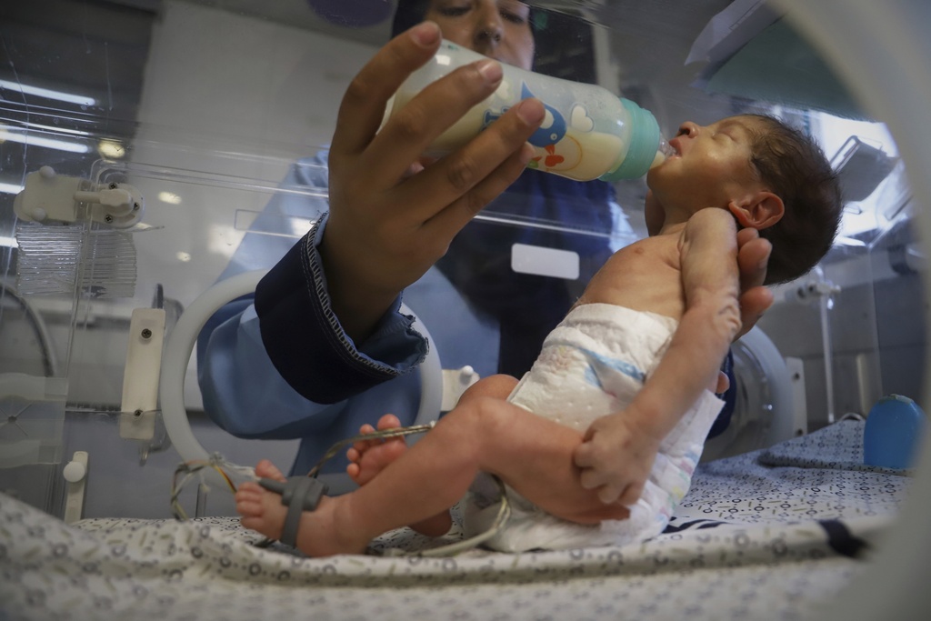 FILE - A nurse feeds a prematurely born baby lying in an incubator at the neonatal intensive care unit of Nasser Hospital in Khan Younis, southern Gaza Strip, Thursday, June 19, 2025. (AP Photo/Mariam Dagga, File)