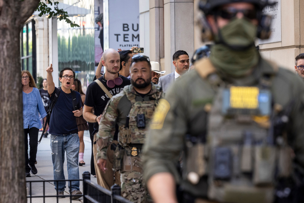 Pedestrians chant, "ICE go home!" as federal immigration agents walk along North Clark Street in the River North neighborhood, Sunday, Sept. 28, 2025, in Chicago. (Ashlee Rezin/Chicago Sun-Times via AP)