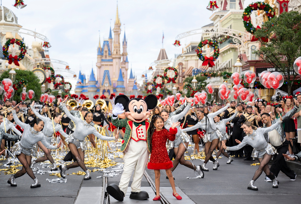 This image released by Disney shows Mickey Mouse and Maia Kealoha from the 40th Anniversary Disney Parks Magical Christmas Day Parade in Orlando, Fla. (Kenslie McGuire/Disney via AP)