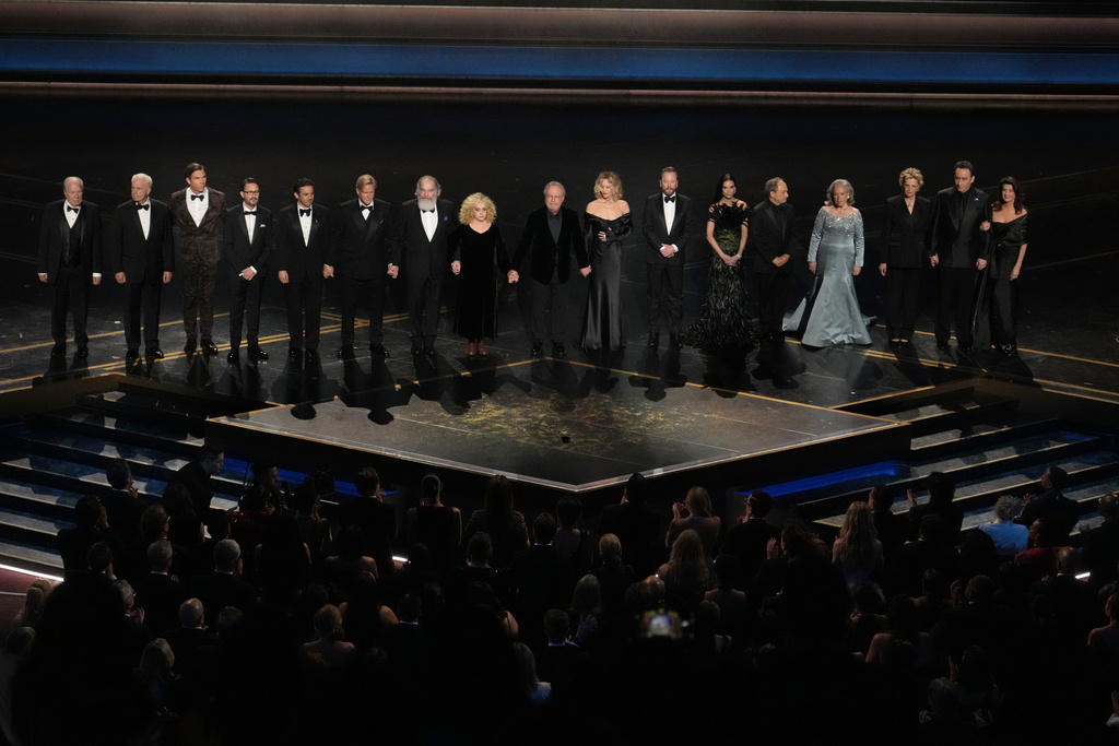 Michael McKean, from left, Christopher Guest, Jerry O'Connell, Will Wheaton, Fred Savage, Cary Elwes, Mandy Patinkin, Carol Kane, Billy Crystal, Meg Ryan, Kiefer Sutherland, Demi Moore, Kevin Pollak, Kathy Bates, Annette Bening, John Cusack, and Daphne Zuniga stand in tribute to Rob Reiner during the Oscars on Sunday, March 15, 2026, at the Dolby Theatre in Los Angeles. (AP Photo/Chris Pizzello)