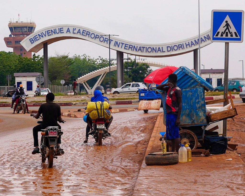 FILE- Motorcyclists ride by the entrance of the airport in Niamey, Niger, Tuesday, Aug. 8, 2023. (AP Photo/Sam Mednick, File)