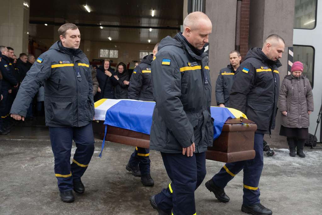 Rescuers carry the coffin of their fellow Oleksandr Zibrov, 36, who was killed in a secondary Russian drone strike on a residential building, at a fire station in Kyiv, Ukraine, Wednesday, Jan. 28, 2026. (AP Photo/Efrem Lukatsky)