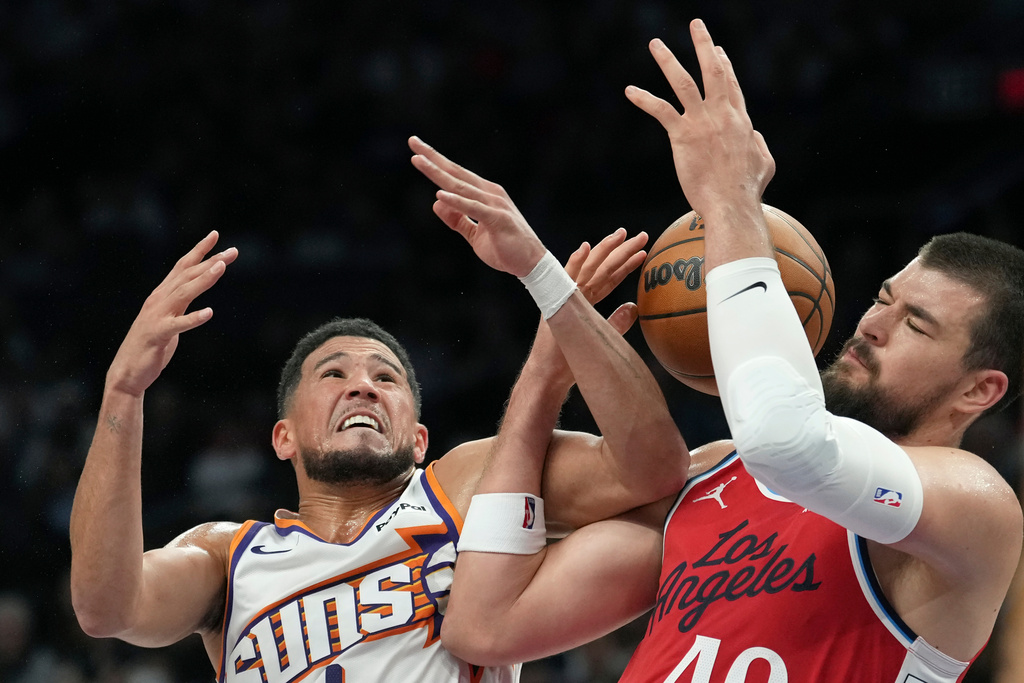Phoenix Suns guard Devin Booker, left, fouls Los Angeles Clippers center Ivica Zubac as they battle for a rebound during the first half of an NBA basketball game Thursday, Nov. 6, 2025, in Phoenix. (AP Photo/Ross D. Franklin)