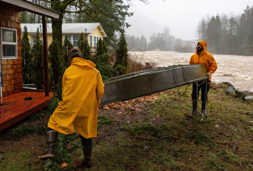 Chad Walker, right, and Adrienne Higbee help an out-of-town neighbor with their property as the Skykomish River rises on Wednesday, Dec. 10, 2025, in Index, Snohomish County, Wash. (Nick Wagner /The Seattle Times via AP)