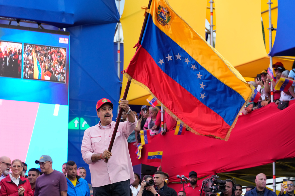 President Nicolas Maduro waves a Venezuelan flag during a swearing-in event for government-organized community committees at the presidential palace in Caracas, Venezuela, Monday, Dec. 1, 2025. (AP Photo/Ariana Cubillos)