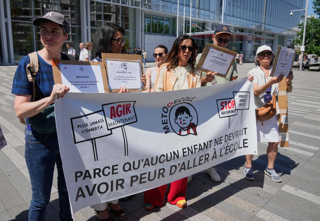 Members and supporters of the #METooEcole (#METooSchool) movement stage a protest to draw attention to a child abuse scandal in France in front of the courthouse in Paris on Tuesday May 26, 2026. The banner reads, in French, "Because no child should ever be afraid to go to school." (AP Photo/Michel Euler)