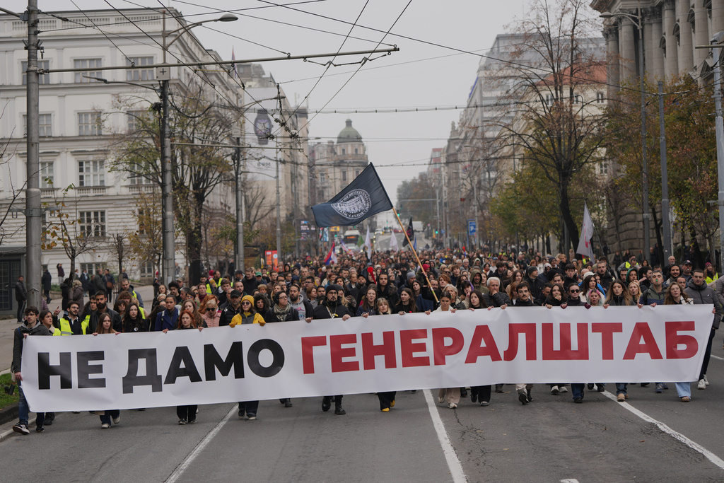 People hold a banner that reads: "We do not give army headquarters" during a protest in front of a military complex that was partially destroyed in a NATO bombing campaign in 1999, after Serbian lawmakers on Friday passed a special law clearing the way for a controversial real estate project that would be financed by an investment company linked to President Trump's son-in-law Jared Kushner, in Belgrade, Serbia, Tuesday, Nov. 11, 2025. (AP Photo/Darko Vojinovic)