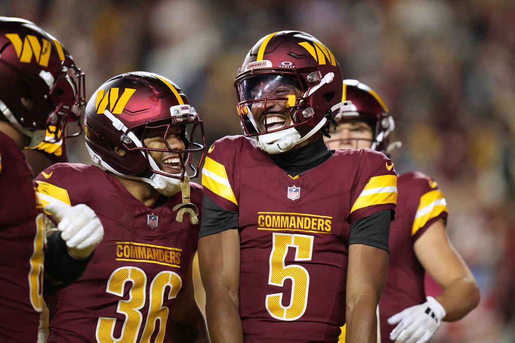 Washington Commanders quarterback Jayden Daniels (5) is congratulated by teammate Chris Rodriguez Jr. (36) after scoring during the first half of a preseason NFL football game Monday, Aug. 18, 2025, in Landover, Md. (AP Photo/Stephanie Scarbrough)