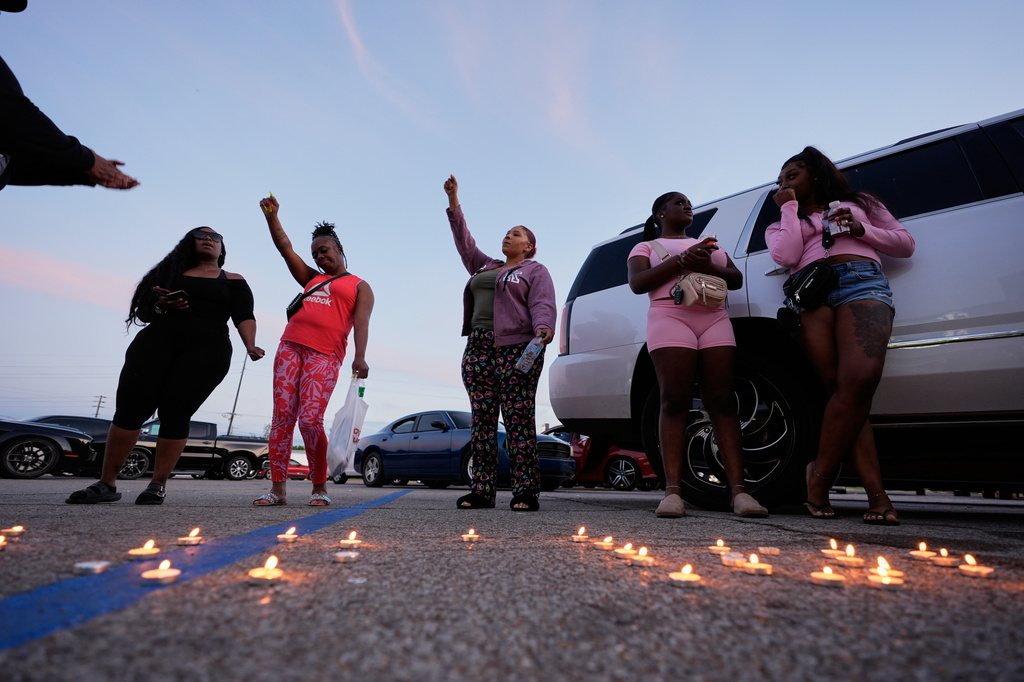 People gesture after lighting candles during a prayer vigil for the victims of a mass shooting earlier in the day, Sunday, April 19, 2026, in Shreveport, La. (AP Photo/Gerald Herbert)