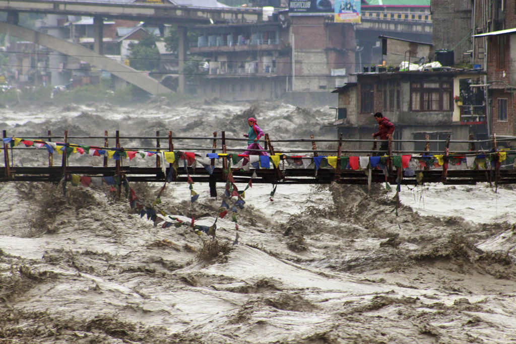FILE - Residents run across a bridge over the flooding Beas River following incessant rains in Kullu, in northern Indian state of Himachal Pradesh, Aug. 26, 2025. (AP Photo/Aqil Khan, File)