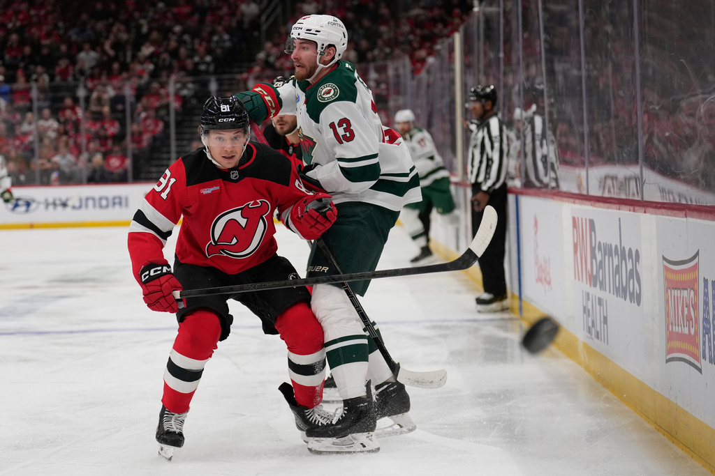 New Jersey Devils' Dawson Mercer, left, and Minnesota Wild's Yakov Trenin (13) look after the puck during the first period of an NHL hockey game Wednesday, Oct. 22, 2025, in Newark, N.J. (AP Photo/Seth Wenig)