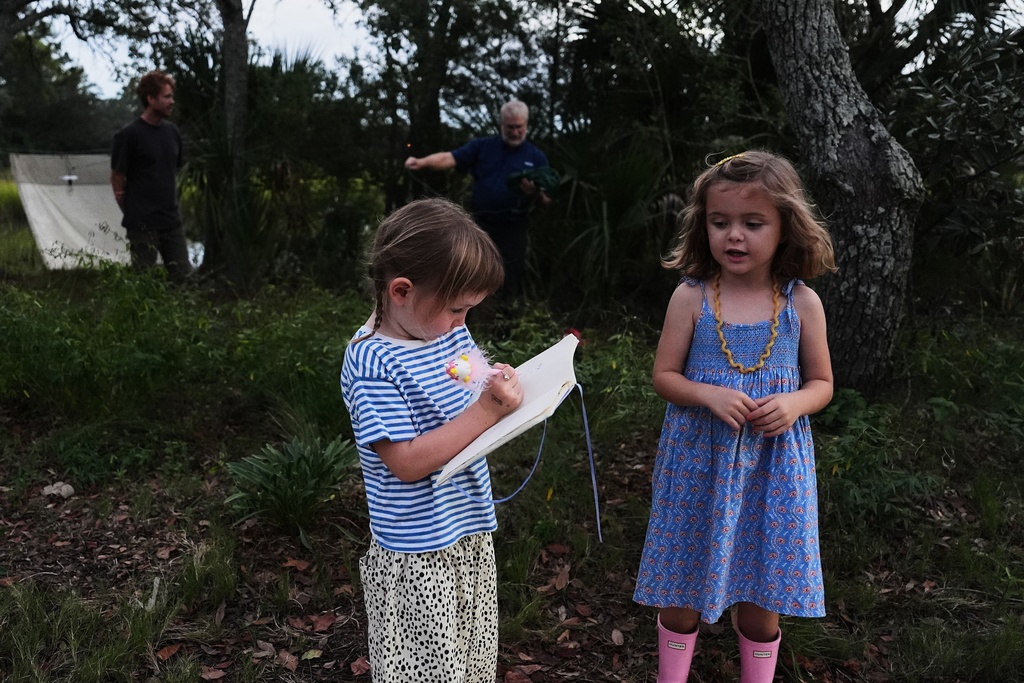 Land Caldwell, front left, draws in a notebook as Agnes Suárez, right, looks on, Tuesday, Oct. 7, 2025, in Charleston, S.C. (AP Photo/Joshua A. Bickel)