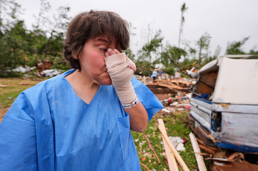 Samantha Perry, who suffered injuries of a bruised hand and bruised right shoulder, reacts among debris at Gene's Mobile Home Supply, a trailer park in Bogue Chitto, Miss., Thursday, May, 7, 2026, after a tornado cut across the state. (AP Photo/Gerald Herbert)
