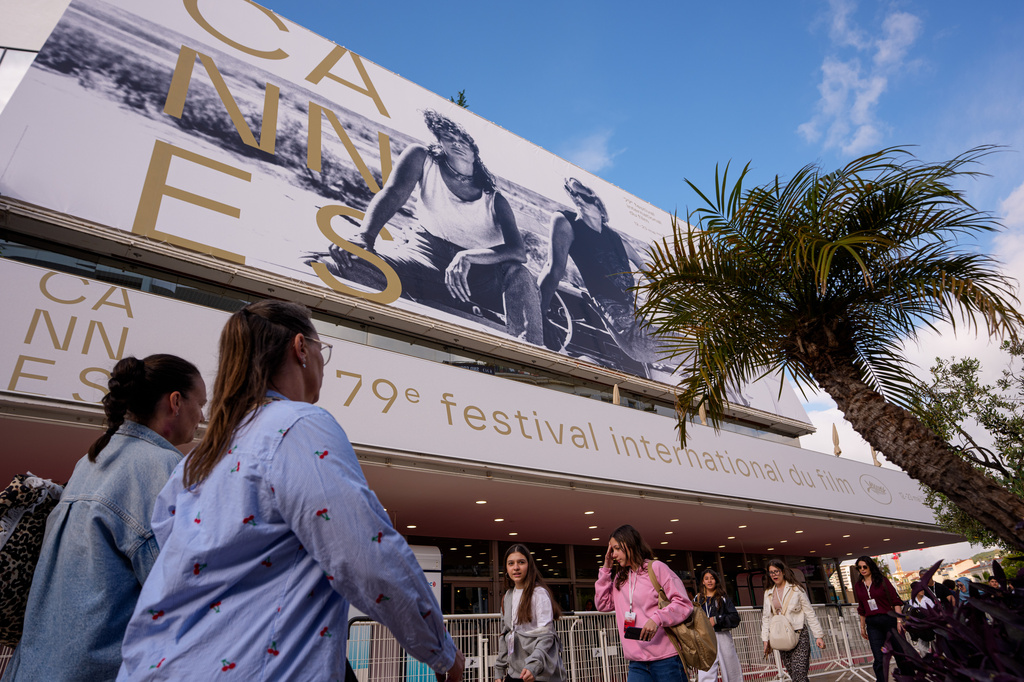 People walk past the Palais des Festivals during preparations for the 79th international film festival, Cannes, southern France, Monday, May 11, 2026. (AP Photo/Andreea Alexandru)