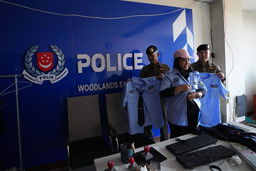 A Thai journalist wears a fake police uniform at a mock-up set resembling a police station inside a scam compound in O'Smach, Cambodia, Monday, Feb. 2, 2026. (AP Photo/Sakchai Lalit)