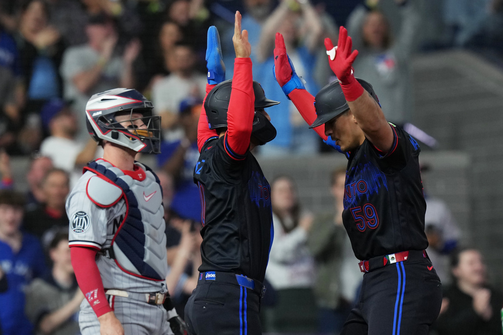 Toronto Blue Jays' Brandon Valenzuela, right, celebrates after his two-run home run with Andres Gimenez, center, in front of Minnesota Twins catcher Ryan Jeffers, left, during fourth-inning baseball game action in Toronto, Friday, April 10, 2026. (Chris Young/The Canadian Press via AP)