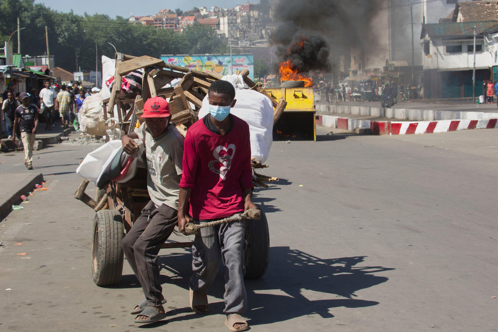 Street vendors pull a cart filled with their merchandise as police clash with demonstrators during a protest calling for the president to step down in Antananarivo, Madagascar, Thursday, Oct. 9, 2025. (AP Photo/Alexander Joe)