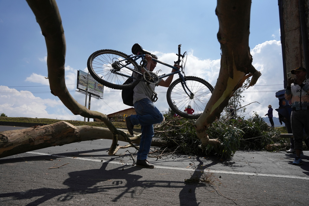 A pedestrian traverses barricades placed by anti-government protesters on the Pan-American Highway, in Otavalo, Ecuador, Monday, Sept. 22, 2025. (AP Photo/Carlos Noriega)