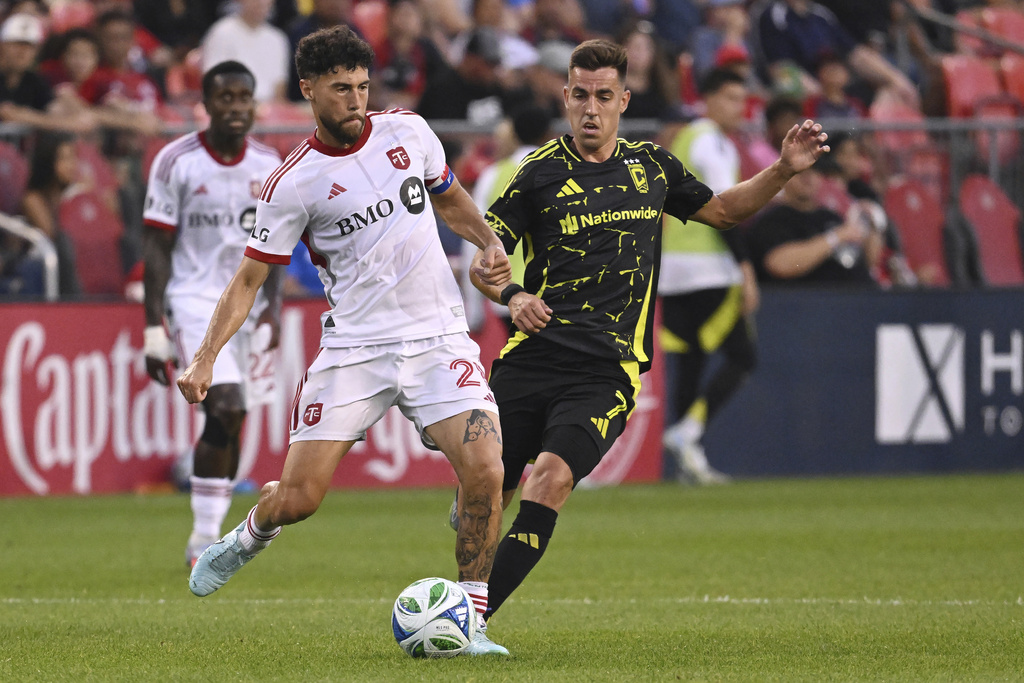 Toronto FC's Jonathan Osorio (21) moves the ball past Columbus Crew's Dylan Chambost during the first half of an MLS soccer game in Toronto on Saturday, Aug. 16, 2025. (Jon Blacker/The Canadian Press via AP)