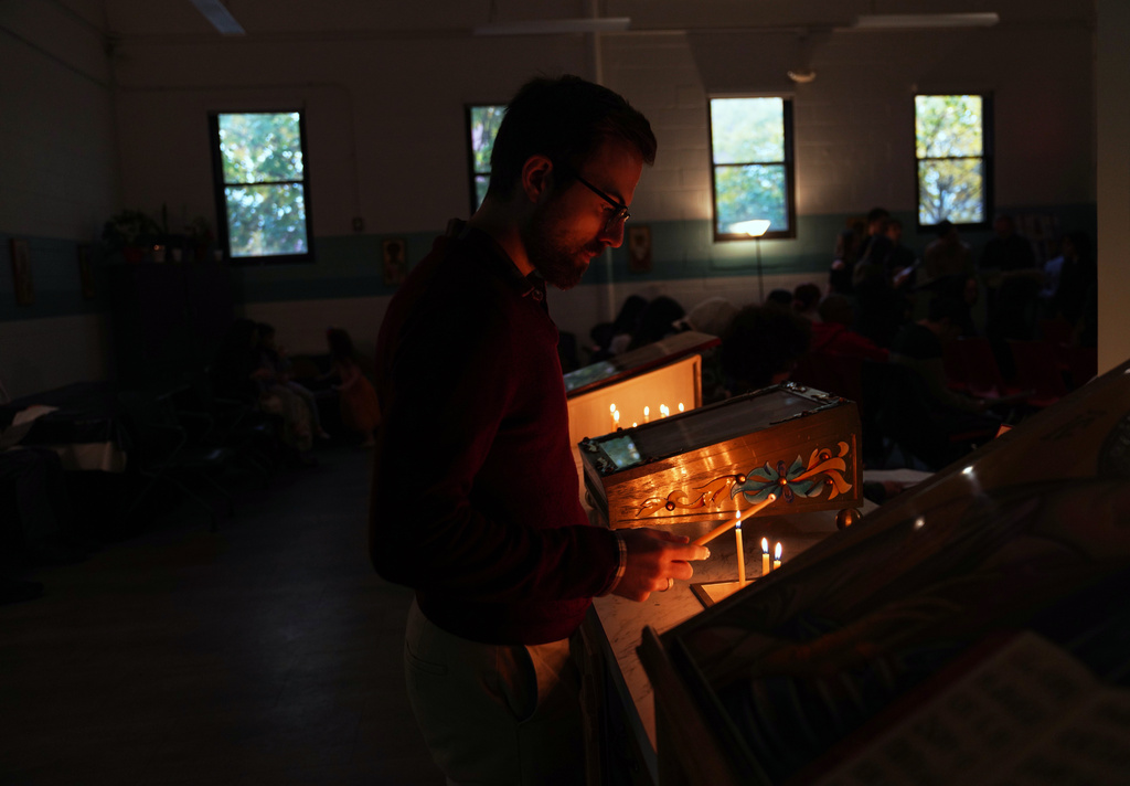 A man lights a candle before service at St. Moses the Black Orthodox Church, Sunday, Nov. 9, 2025, in Pittsburgh. (AP Photo/Jessie Wardarski)