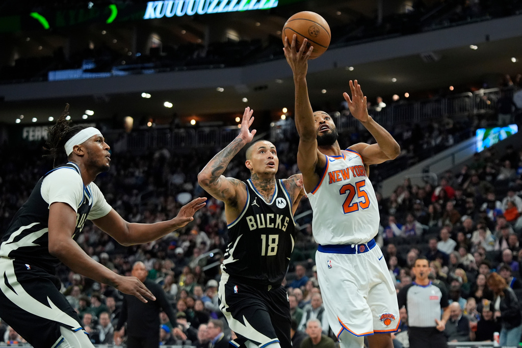 New York Knicks' Mikal Bridges (25) shoots against Milwaukee Bucks' Kyle Kuzma (18) during the second half of an NBA basketball game Friday, Feb. 27, 2026, in Milwaukee. (AP Photo/Aaron Gash)