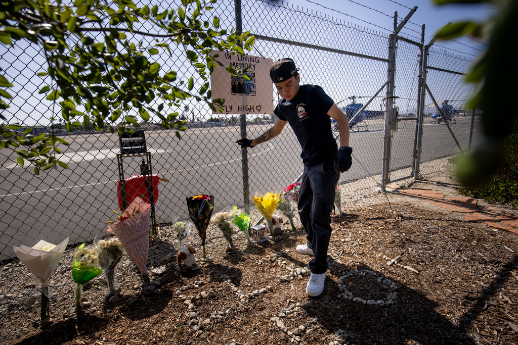 A person adjusts flowers at a memorial for Eliana Moreno and George Marciniw, who died in a helicopter crash the day prior while covering an accident for a television station, at the site where their helicopter used to park at Whiteman Airport in Los Angeles, Wednesday, Sept. 16, 2026. (AP Photo/Ethan Swope) ADDITION: Adds in a helicopter crash the day prior while covering an accident for a television station.