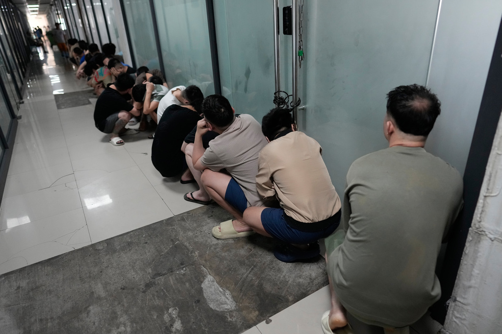 Rescued scam workers hide their faces from the camera as they wait to go the canteen at the Presidential Anti-Organized Crime Commission temporary detention center, a former scam compound, in Pasay, Philippines, Tuesday, June 3, 2025. (AP Photo/Aaron Favila)