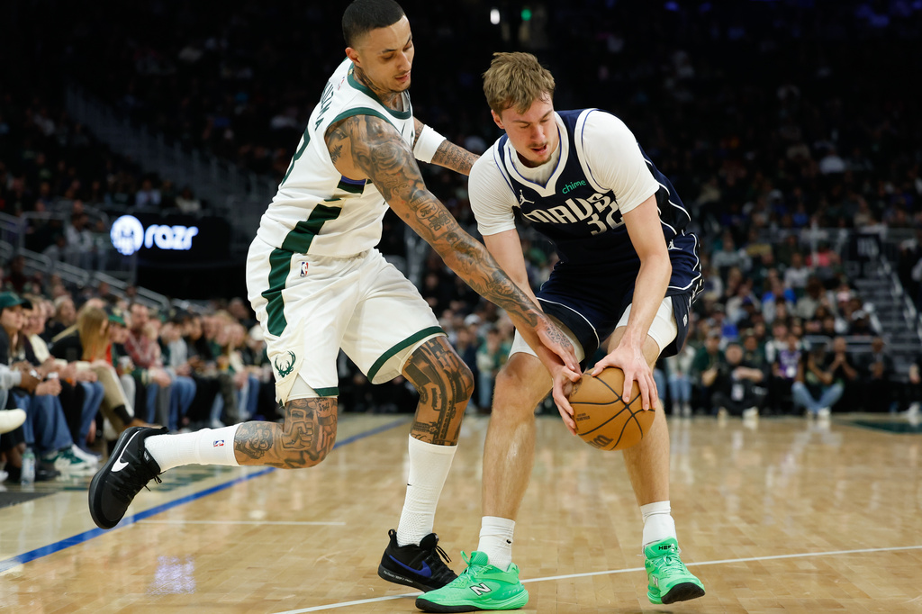Milwaukee Bucks forward Kyle Kuzma (18) and Dallas Mavericks forward Cooper Flagg (32) reach for the ball during the first half of an NBA basketball game Tuesday, March 31, 2026, in Milwaukee. (AP Photo/Jeffrey Phelps)