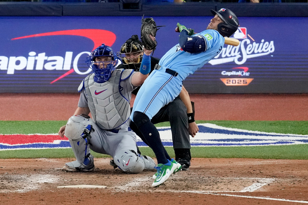 Toronto Blue Jays' George Springer, right, takes an inside pitch as Los Angeles Dodgers' Will Smith makes the catch during the eighth inning in Game 6 of baseball's World Series, Friday, Oct. 31, 2025, in Toronto. (AP Photo/Ashley Landis)