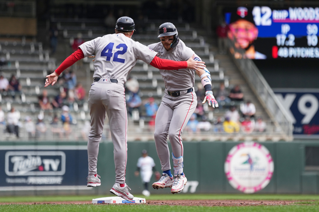 Boston Red Sox's Trevor Story, right, celebrates with third base coach Kyle Hudson after hitting a three-run home run during the third inning of a baseball game against the Minnesota Twins Wednesday, April 15, 2026, in Minneapolis. All players and coaches are wearing No. 42 in honor of Jackie Robinson Day. (AP Photo/Abbie Parr)