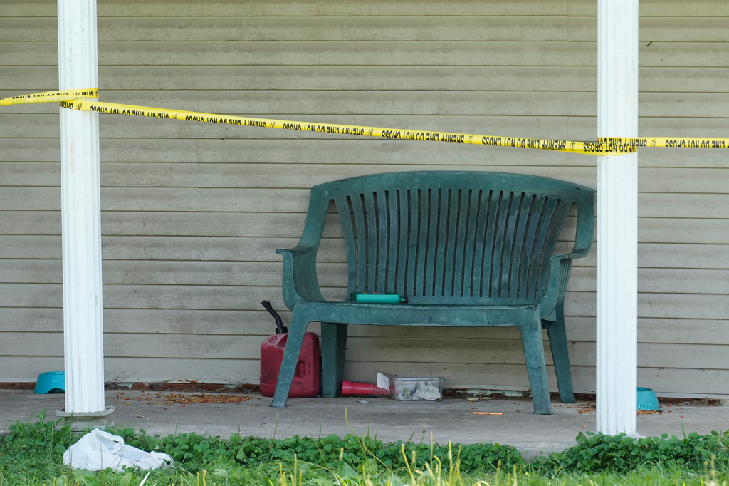 A bench and items including a gas can are seen beyond police tape at a home where authorities say they removed 16 children and arrested four adults in Hamden, Ohio, Wednesday, July 1, 2026. (AP Photo/Carolyn Kaster)