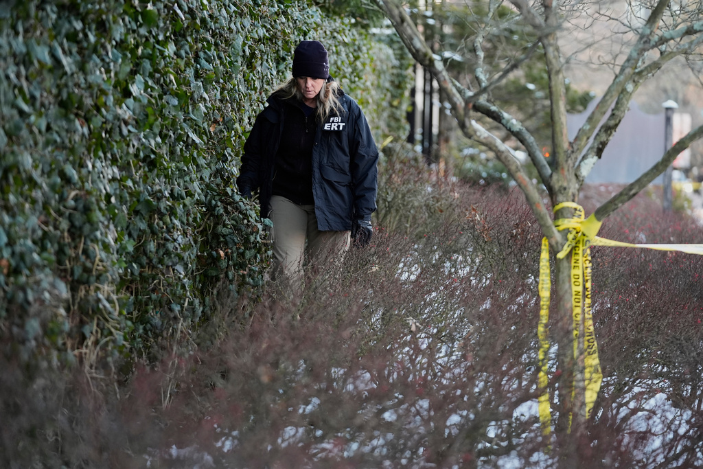 A member of the FBI Evidence Response Team searches for evidence near an ivy-covered wall following the shooting at Brown University, Monday, Dec. 15, 2025, in Providence, R.I. (AP Photo/Robert F. Bukaty)