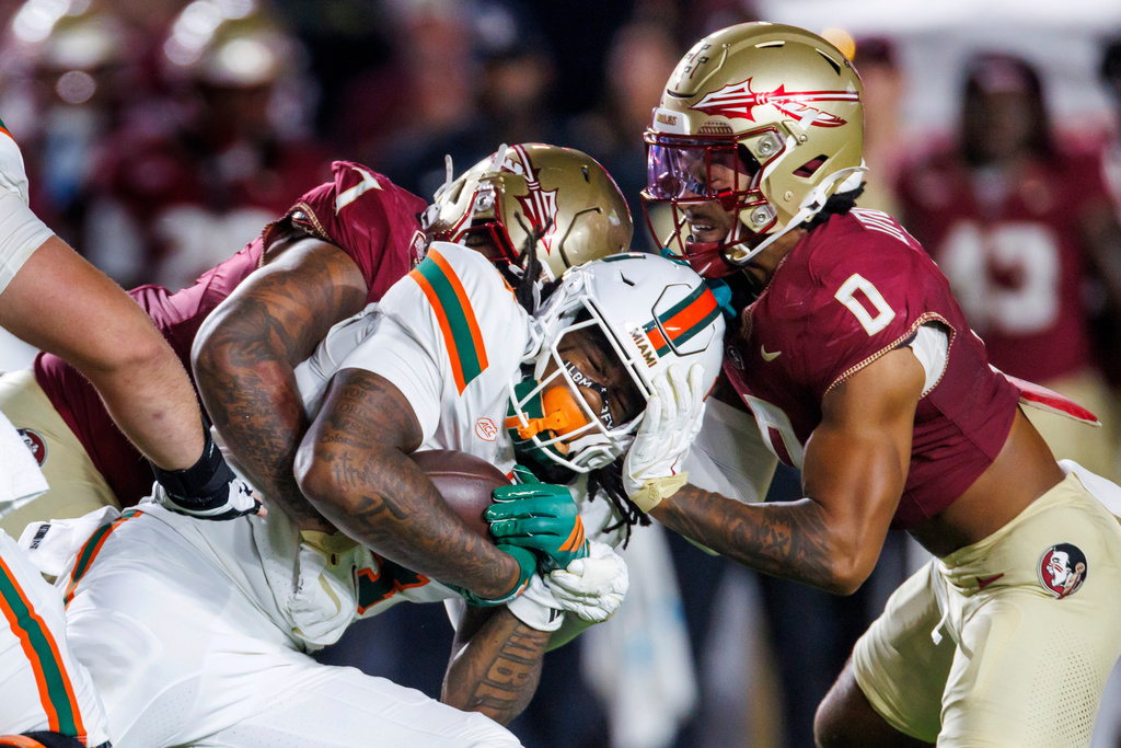 Miami running back Mark Fletcher Jr. (4) is stopped by Florida State linebacker Stefon Thompson (7) and defensive back Earl Little Jr. (0) during the first half of an NCAA college football game, Saturday, Oct. 4, 2025, in Tallahassee, Fla. (AP Photo/Colin Hackley)