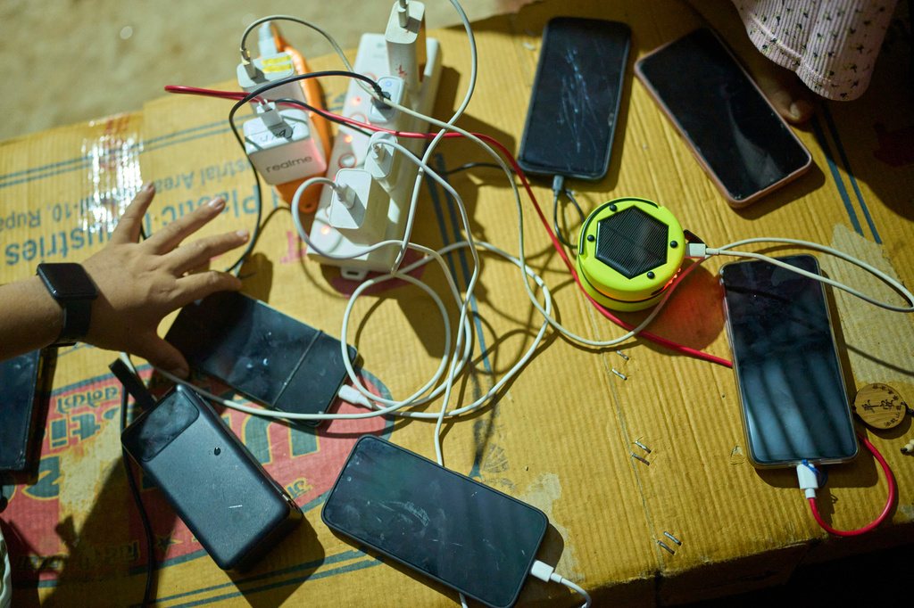 Survivors of a flash flood charge their cell phone at a temporary holding center in Nuwakot, Nepal, Sept. 22, 2026. (AP Photo/Niranjan Shrestha)